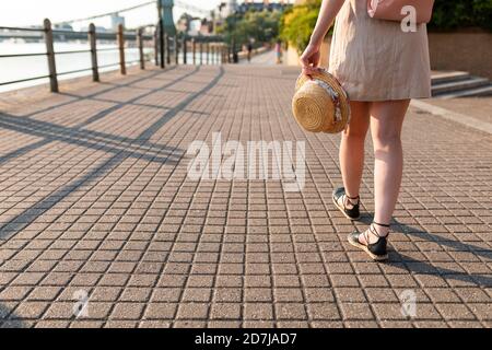 Jambes de femme marchant sur le trottoir le long de la rivière Banque D'Images