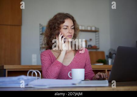 Femme travaillant assis près d'une table à la maison Banque D'Images