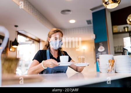 Une femme Barista sert du café au comptoir dans le café Banque D'Images
