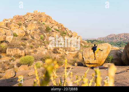 Grimpeur de roche se trouvant au-dessus d'un rocher couché à pied de colline rocheuse Banque D'Images