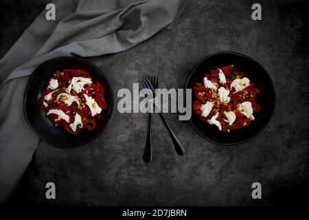 Deux bols de salade végétarienne avec poivrons rouges, mozzarella, pignons de pin rôtis, persil et ciboulette Banque D'Images