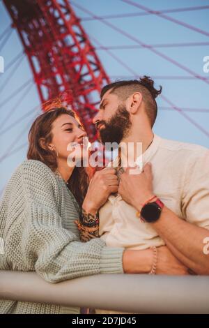 Couple debout sur le pont en ville pendant le coucher du soleil Banque D'Images