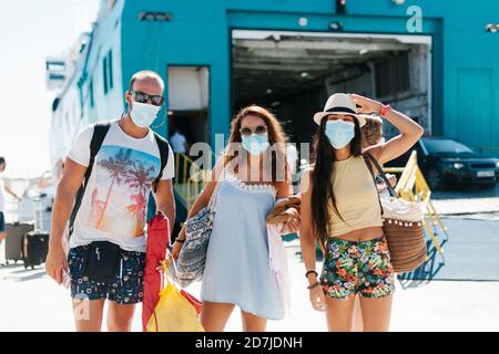 Amis portant des masques debout contre un bateau de croisière au port Banque D'Images