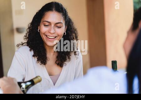 Un ami qui sert du champagne dans un verre de femme tout en étant assis à arrière-cour Banque D'Images