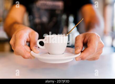 Un barista masculin sert du café au comptoir du café Banque D'Images