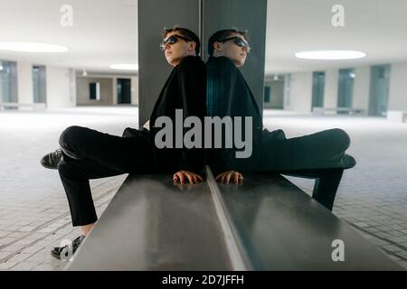 TRANS jeune homme portant des lunettes de soleil noires assis sur le siège fenêtre au sous-sol Banque D'Images