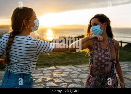 Femmes dans le visage protecteur masques coude bumping contre le ciel pendant Éclosion de la COVID-19 Banque D'Images