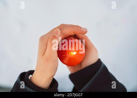 Gros plan des mains de la jeune femme tenant la bougie sur la neige couverte terre Banque D'Images