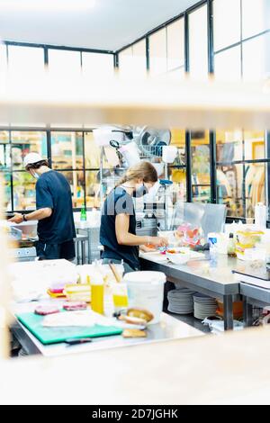 Les chefs cuisinent dans une cuisine commerciale au restaurant vu par la fenêtre Banque D'Images