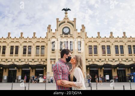 Couple avec masque facial de protection embrassant dans la rue en ville Banque D'Images