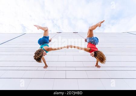 Danseuses aériennes à l'envers en tenant les mains pendant qu'elles sont suspendues à la fenêtre Banque D'Images