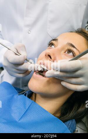 Dentiste en gants examinant la cavité buccale de la patiente à clinique Banque D'Images