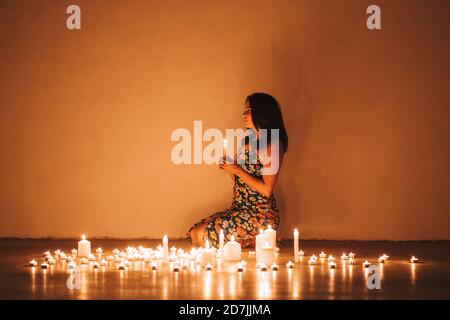 Femme avec bougies allumées dans le salon à la maison Banque D'Images