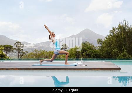 Jeune femme faisant de l'exercice d'étirement près de la piscine Banque D'Images