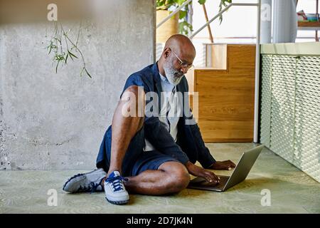 Homme mature travaillant sur un ordinateur portable assis à la maison Banque D'Images