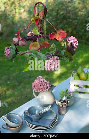 Briy Lamp Shade fait de feuilles de betteraves et d'hortensias en fleurs table basse suspendue dans le jardin Banque D'Images