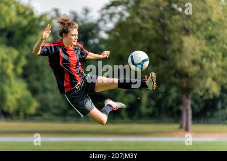 Jeune femme jouant au football sur le terrain Banque D'Images