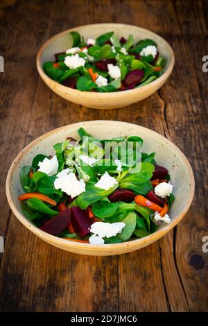 Deux bols de salade végétarienne avec bandes de carottes grillées, betteraves, salade de maïs, fromage de chèvre et oignons espagnols Banque D'Images