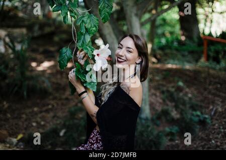 Femme souriante tenant une plante de fleur tout en se tenant au parc Banque D'Images