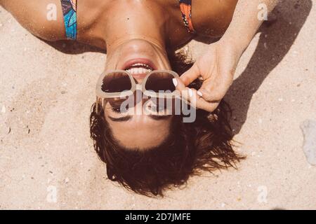 Femme gaie portant des lunettes de soleil tout en étant couché à la plage de Valdevaqueros le jour ensoleillé, Tarifa, Espagne Banque D'Images