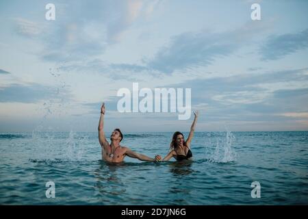 Couple joueur tenant la main en se tenant debout dans l'eau Banque D'Images