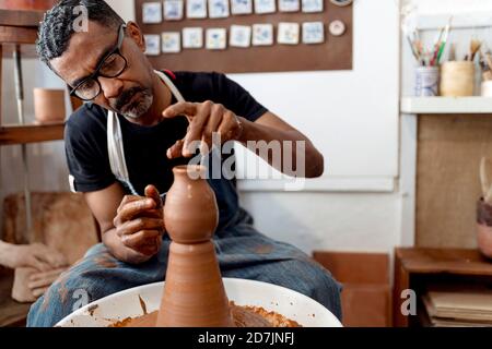 Gros plan de mâle potter en faïence pendant qu'il est assis dans un atelier Banque D'Images