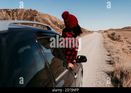 Espagne, Navarre, touriste féminine penchée hors de la fenêtre de voiture au-dessus de la route de terre dans Bardenas Reales Banque D'Images