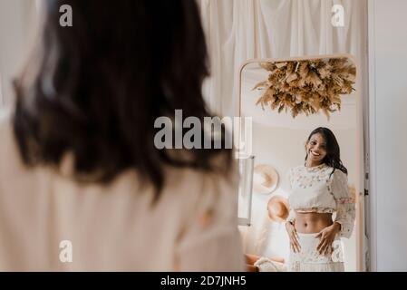 Image reflétant l'image de la mariée souriante regardant dans le miroir au mariage boutique de vêtements Banque D'Images