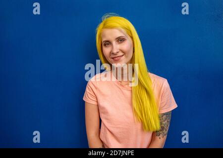 Femme souriante debout contre le mur bleu Banque D'Images