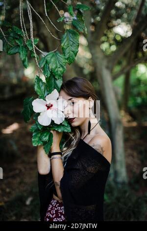 Femme tenant une plante de fleur en se tenant au parc Banque D'Images