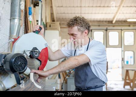 Homme utilisant une scie électrique en se tenant à l'atelier Banque D'Images