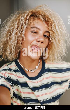 Femme aux cheveux bouclés blonds prenant le selfie tout en collant timon Banque D'Images