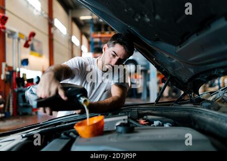 Remplissage d'huile moteur automatique par un mécanicien en position de garage Banque D'Images