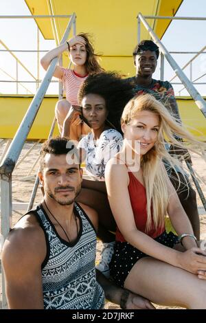 Jeunes amis assis sur les marches de la cabane du maître-nageur sur la plage par beau temps Banque D'Images