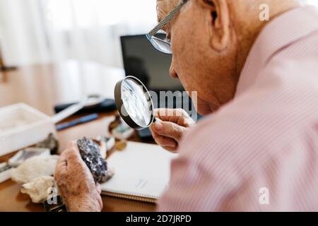 Homme âgé à la retraite regardant à travers la loupe au minéral Banque D'Images
