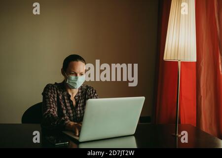 Femme d'affaires portant un masque de protection travaillant sur un ordinateur portable au bureau Banque D'Images