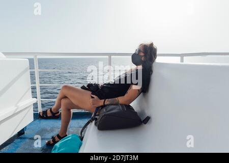 Femme portant un masque de repos pendant qu'elle est assise dans une embarcation de passager Banque D'Images