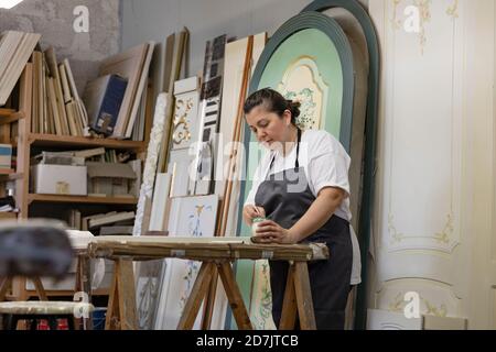 Femme mûre peint la porte en se tenant au studio d'art Banque D'Images