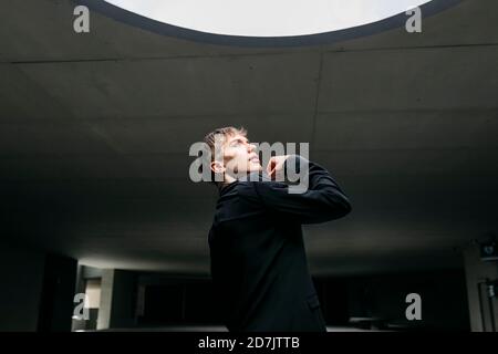 Homme non binaire portant un costume noir dansant au sous-sol Banque D'Images