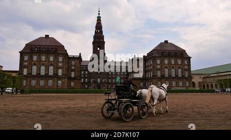 Copenhague, Danemark - 04/30/2019: Lady formant des chevaux de calèche dans l'arène équestre (Ridebane) en face du château historique de Christiansborg Slot. Banque D'Images