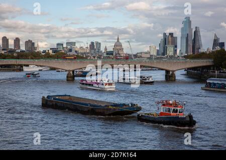 Barges remorquées par un bateau à remorqueurs sur la Tamise avec la cathédrale St Paul et la ville de Londres au loin du pont de Waterloo, Angleterre, Royaume-Uni Banque D'Images