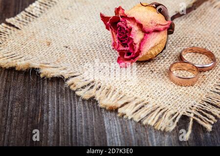 Anneaux de mariage et roses fleurs séchées sur fond de bois. Banque D'Images