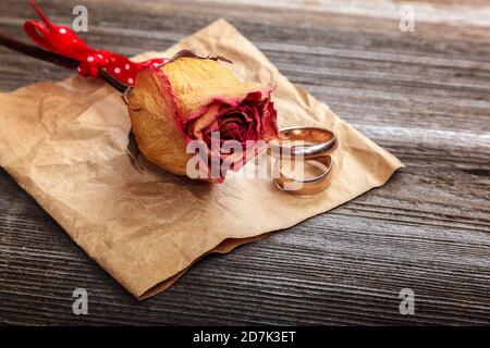 Anneaux de mariage et roses fleurs séchées sur fond de bois. Banque D'Images