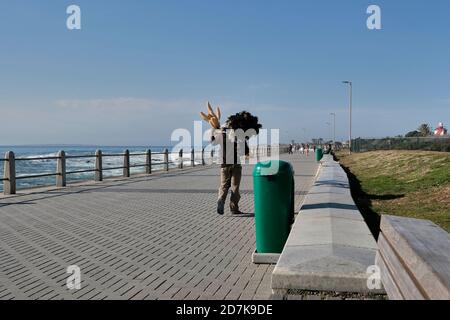 Vendeur de rue photographié de derrière sur la promenade de Sea point au Cap, en Afrique du Sud. Banque D'Images