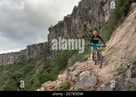 Un homme qui descend un vélo de montagne sur un étroit sentier rocky dans un canyon Banque D'Images