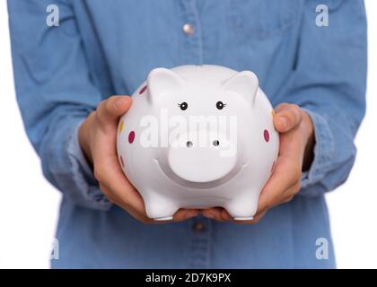 Belle adolescente tient une banque de porc dans ses mains, isolée sur fond blanc Banque D'Images