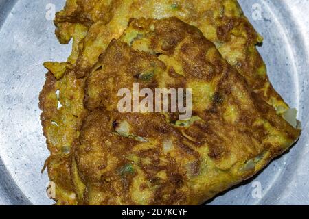 Omelette aux œufs servie sur une assiette en acier après une friture profonde et savoureuse. Banque D'Images