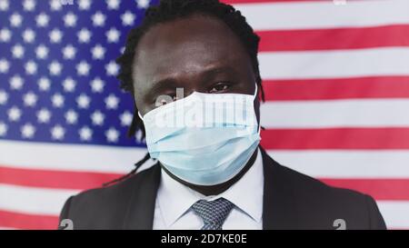 African American in face Mask regarder l'appareil photo - drapeau américain en arrière-plan - gros plan. Photo de haute qualité Banque D'Images
