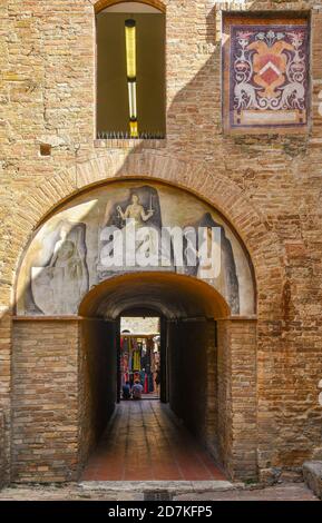 Cour du Palazzo Comunale avec une fresque en monochrome par Vincenzo Tamagni sur un passage voûté menant à la Piazza del Duomo, San Gimignano, Italie Banque D'Images