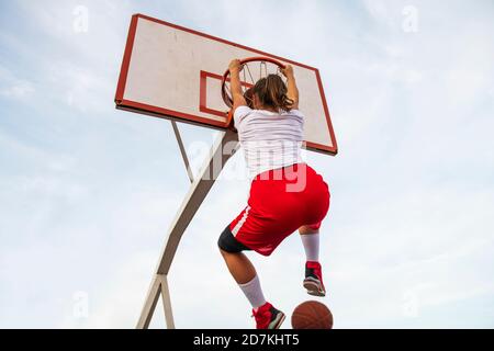 Femmes jouant au basket-ball sur le terrain de rue. Une femme jouant au streetball fait du slam punk dans un match de basket-ball. Banque D'Images